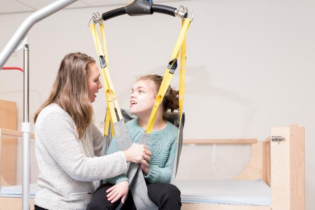 Carer helping a disabled child with a harness