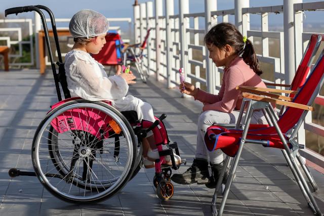 Girl in a wheelchair playing with a girl sat in a chair