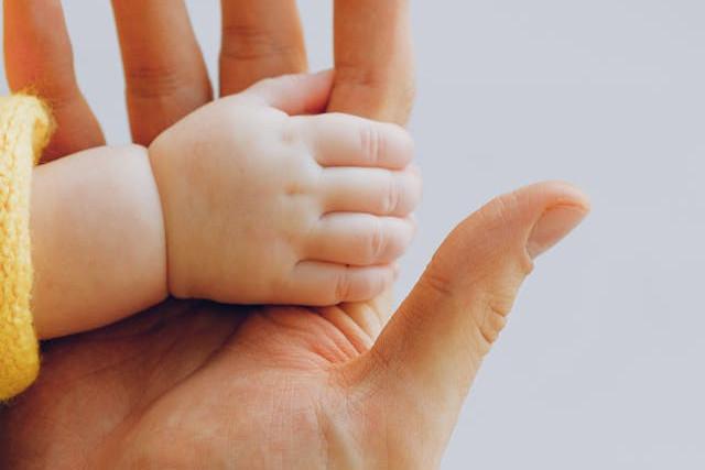 Hand of a baby holding a mans hand