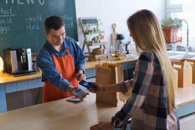 Down Syndrome waiter taking contactless smartphone payment from customer