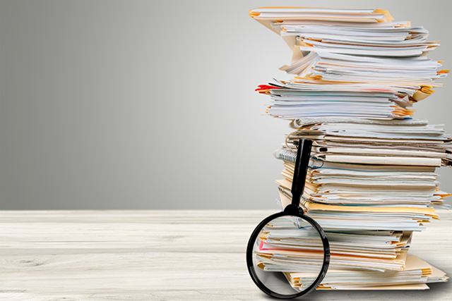 A photograph of a pile of books with a magnifying glass resting on them