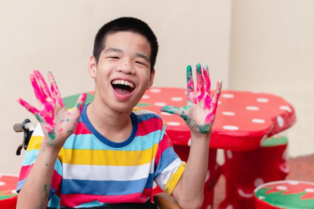 Disabled boy smiling with paint on his hands