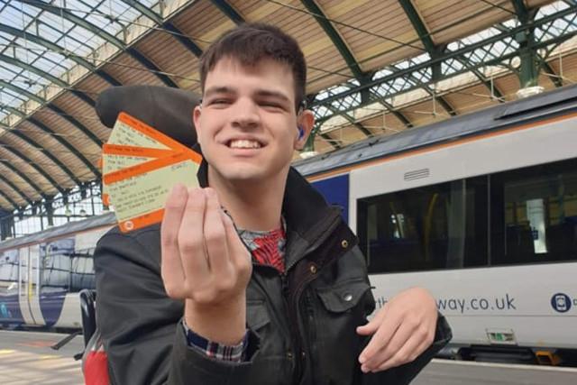 A boy in a wheelchair holding train tickets