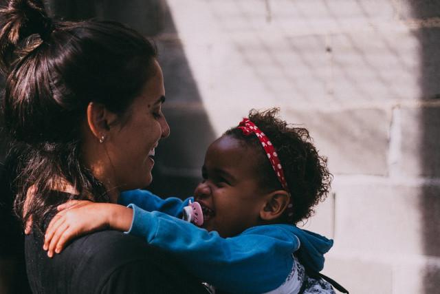 A child and her mother smiling at each other
