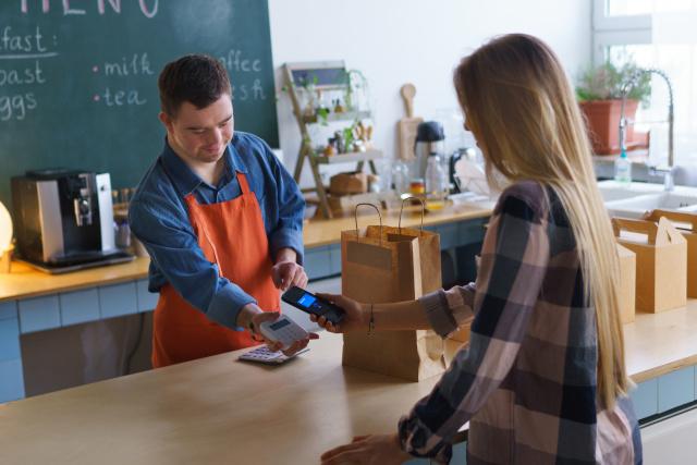 A waiter with down syndrome serving a customer