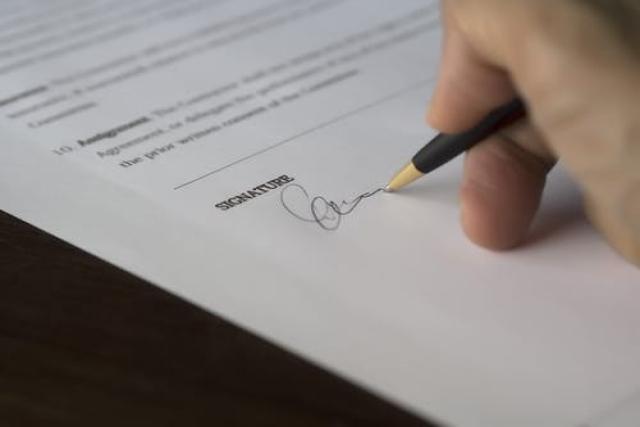 Hand holding a pen signing a document